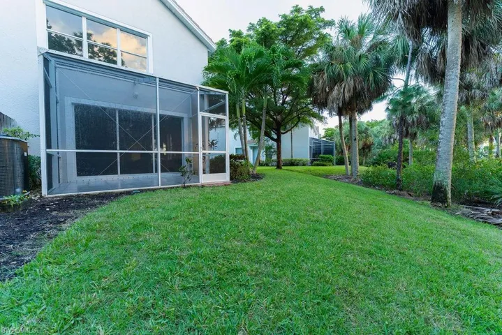 View of grassy yard with a lanai and a sunroom