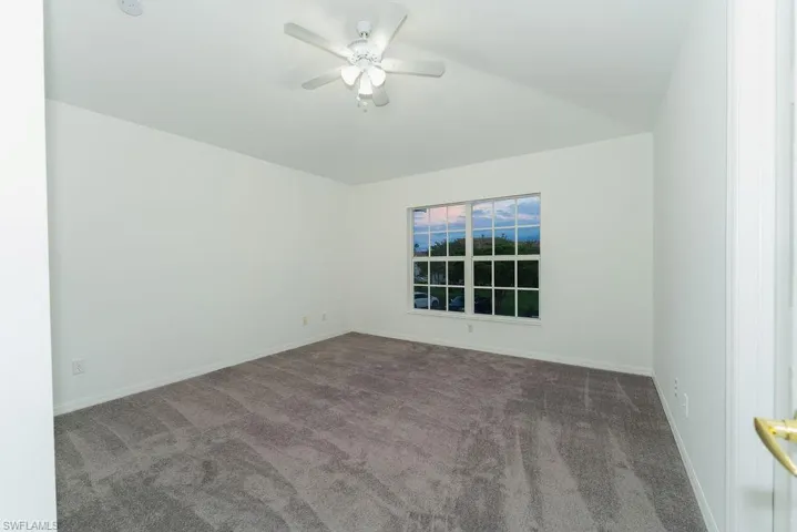 Spare room with carpet floors, ceiling fan, and lofted ceiling