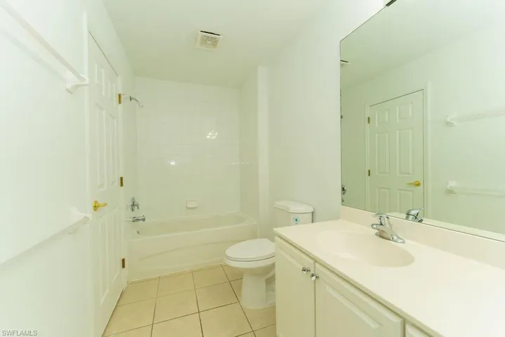 Full bathroom with light tile patterned floors, shower / bath combination, and vanity