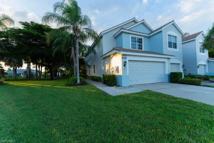View of front facade featuring a garage, concrete driveway, a front yard, and stucco siding