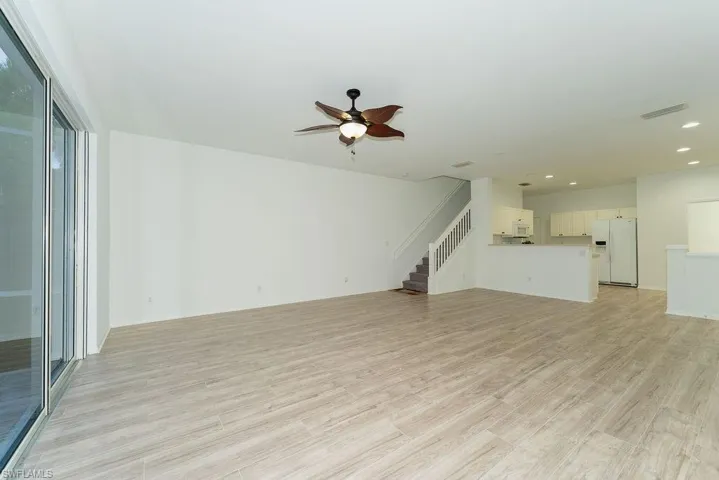 Unfurnished living room with light wood-type flooring, ceiling fan, stairs, and recessed lighting