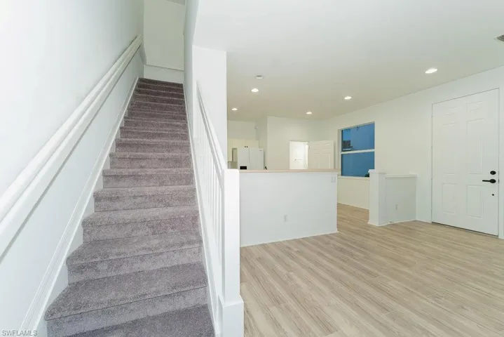Stairway featuring wood finished floors and recessed lighting