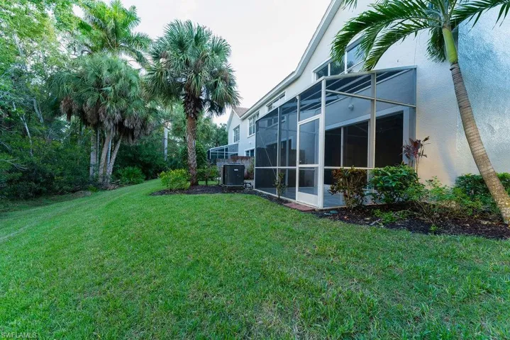 View of grassy yard with a sunroom and a lanai