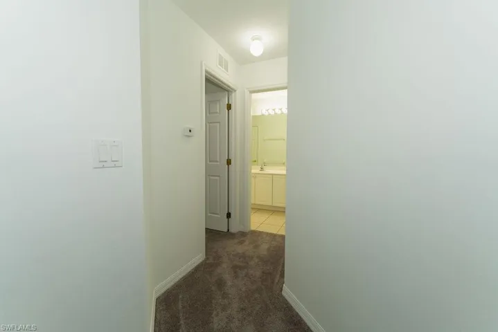 Hallway with dark colored carpet and baseboards