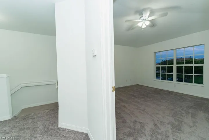 Empty room with light carpet and a ceiling fan