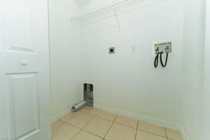 Laundry area featuring light tile patterned floors, hookup for a washing machine, and hookup for an electric dryer