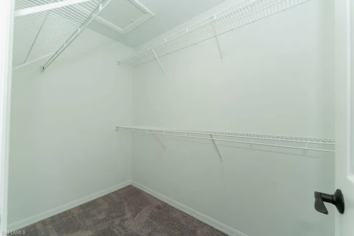 Spacious closet with dark colored carpet and attic access