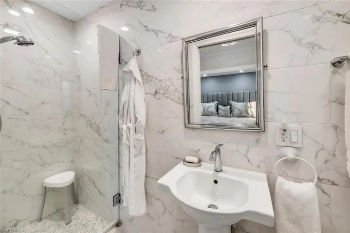 Bathroom featuring tile walls, sink, and a shower glass door