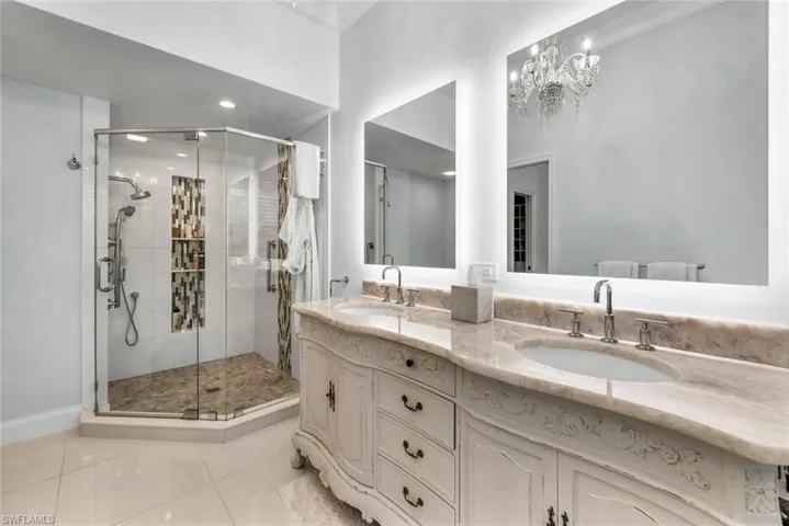 Bathroom featuring double vanity, a chandelier, tile flooring, ornamental molding, and walk in shower