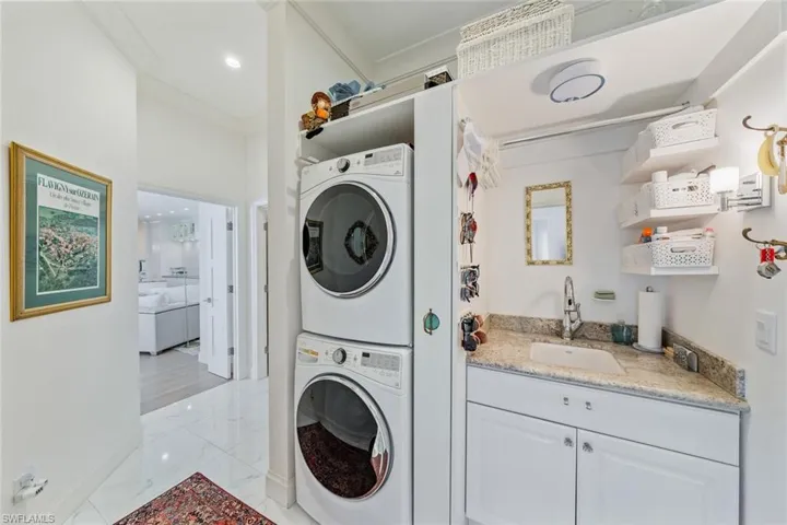 Washroom featuring stacked washing machine and dryer, folding area and sink