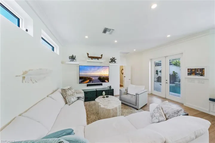 Living room with crown molding, french doors, and light wood-type flooring