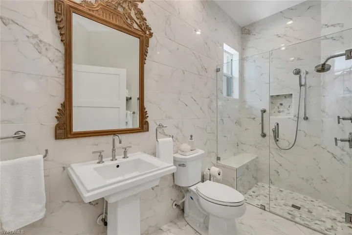 Bathroom featuring tile flooring, an enclosed shower, tile walls, sink, and toilet