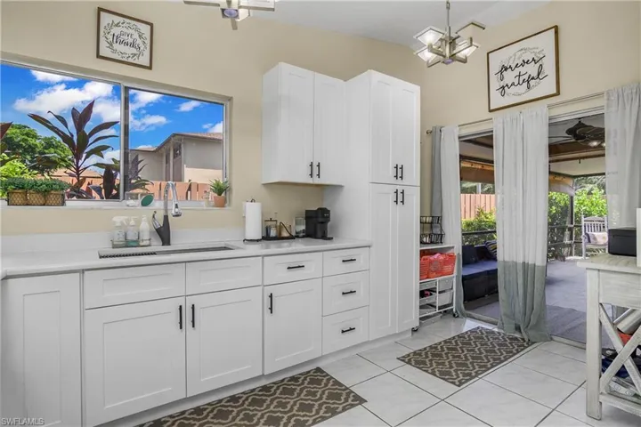 Kitchen with white cabinets, an inviting chandelier, sink, lofted ceiling, and light tile patterned flooring