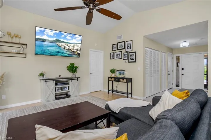 Living room with lofted ceiling, ceiling fan, and light wood-type flooring