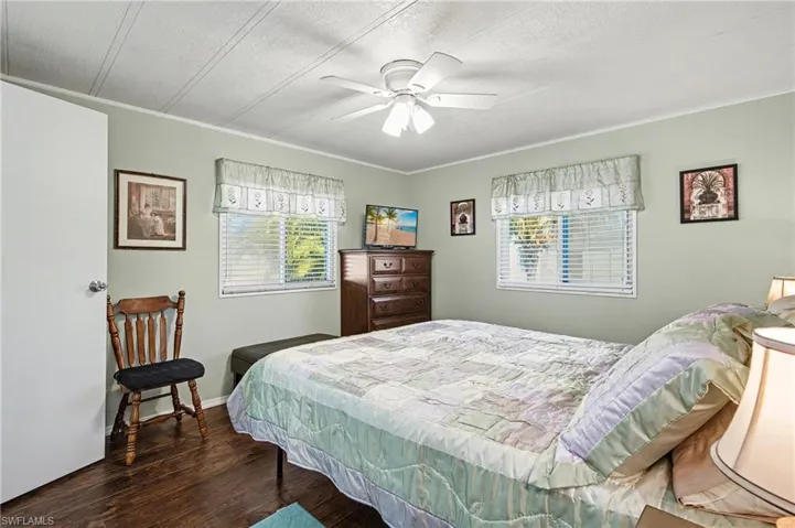 Bedroom with dark wood-style floors, a ceiling fan, and ornamental molding