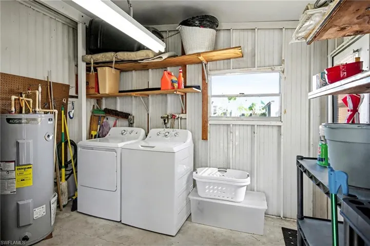 Washroom with electric water heater, concrete flooring, and separate washer and dryer
