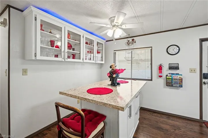 Kitchen with white cabinets, light countertops, a breakfast bar area, a center island, and glass insert cabinets