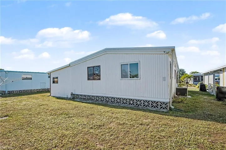View of property exterior featuring a lawn and a central AC unit