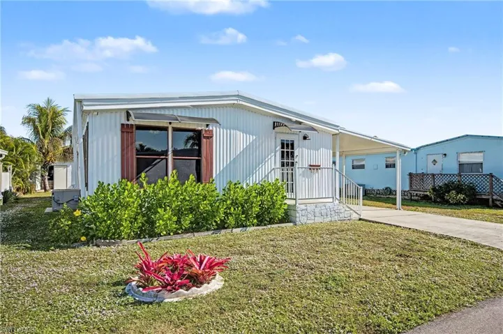 Manufactured / mobile home with a front yard, driveway, and a carport