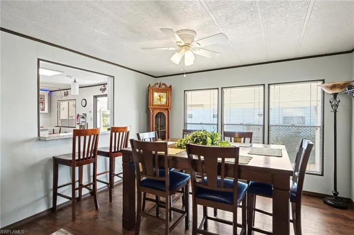 Dining space with dark wood-style flooring, a ceiling fan, ornamental molding, and a textured ceiling