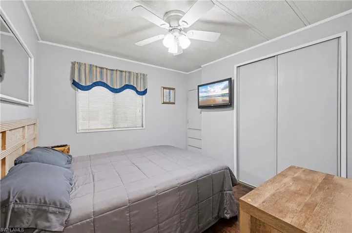 Bedroom featuring a ceiling fan, a closet, dark wood finished floors, and ornamental molding