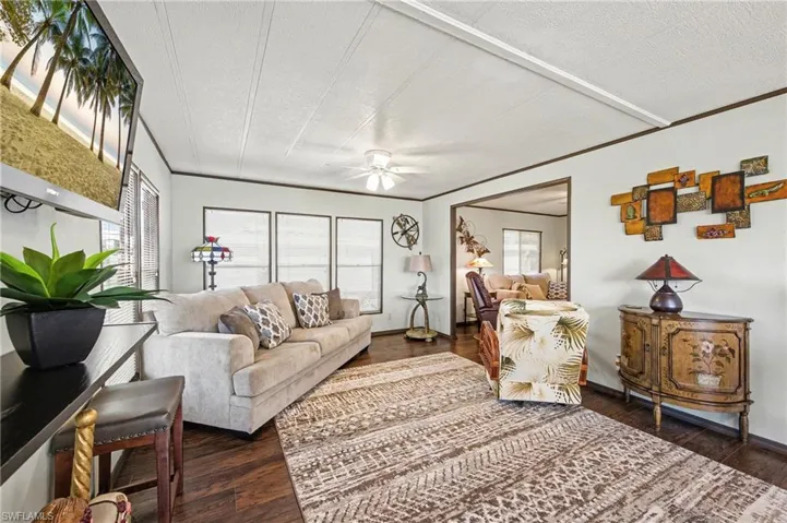Living room featuring dark wood-style flooring, a textured ceiling, and a ceiling fan