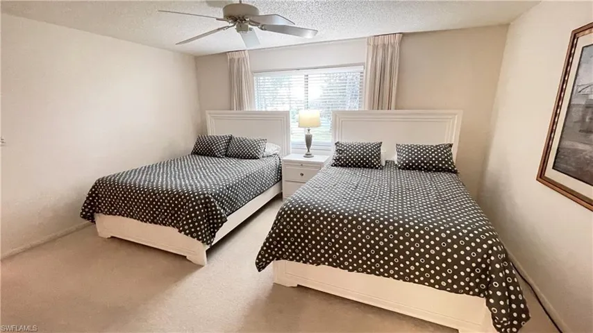 Carpeted primary bedroom with ceiling fan and double queen beds.