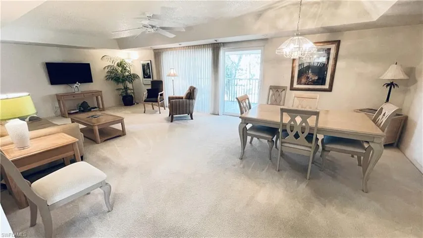 Dining room with light carpet, a ceiling fan, and a chandelier.