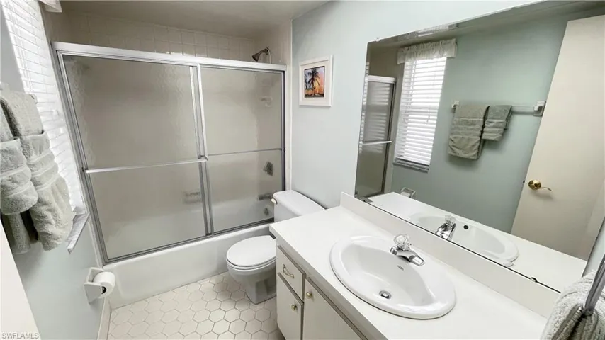 Bathroom featuring vanity, glass enclosed tub / shower combo, and light tile patterned flooring.