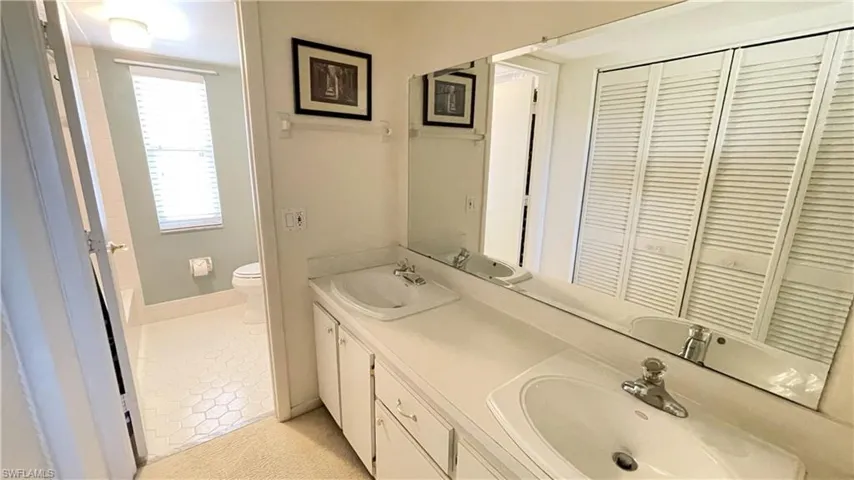 Bathroom with double vanity, a closet, and light tile patterned flooring