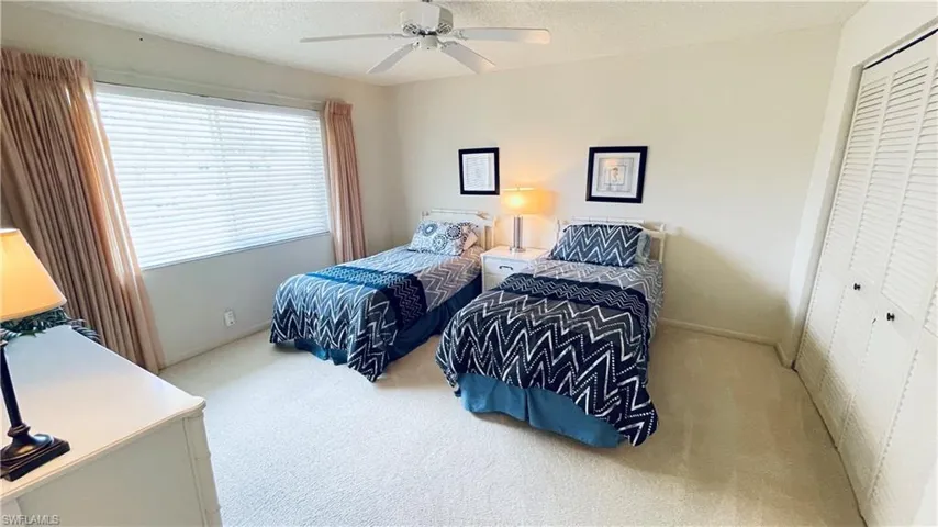 Carpeted bedroom with double closet, and ceiling fan.
