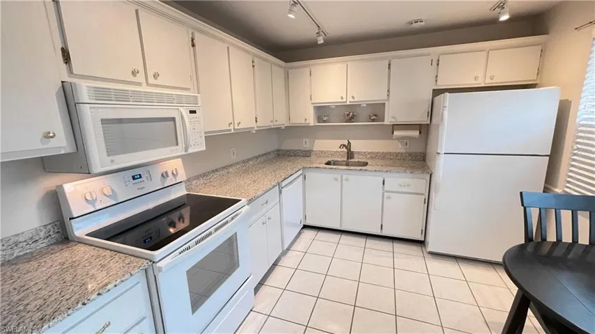 Kitchen featuring white appliances, open shelves, light stone counters, rail lighting, and light tile patterned flooring