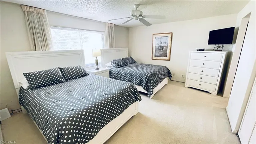 Bedroom with light colored carpet, ceiling fan and double queen beds.