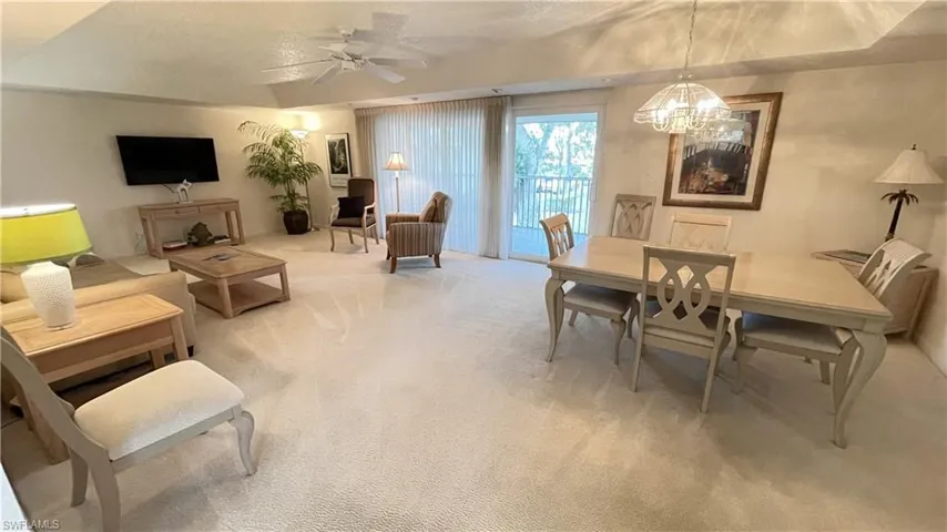 Living/Dining area with light colored carpet, ceiling fan, and hanging lights