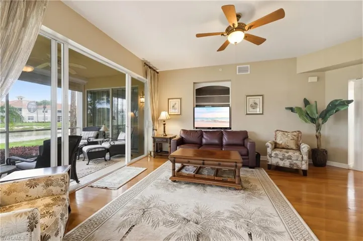 Living area featuring wood-finish flooring, a ceiling fan, and sliding glass doors opening to a screened lanai