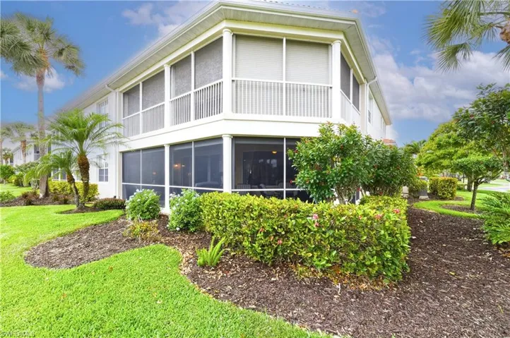 Exterior featuring a screened-in lanai, upper-level screened balcony with white railing, and mature landscaping