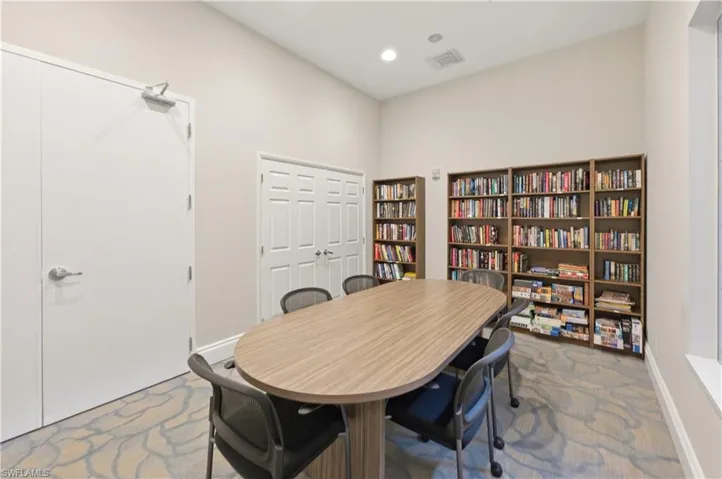 Spacious meeting room featuring a large oval table, integrated bookshelves, recessed lighting, and patterned carpeting