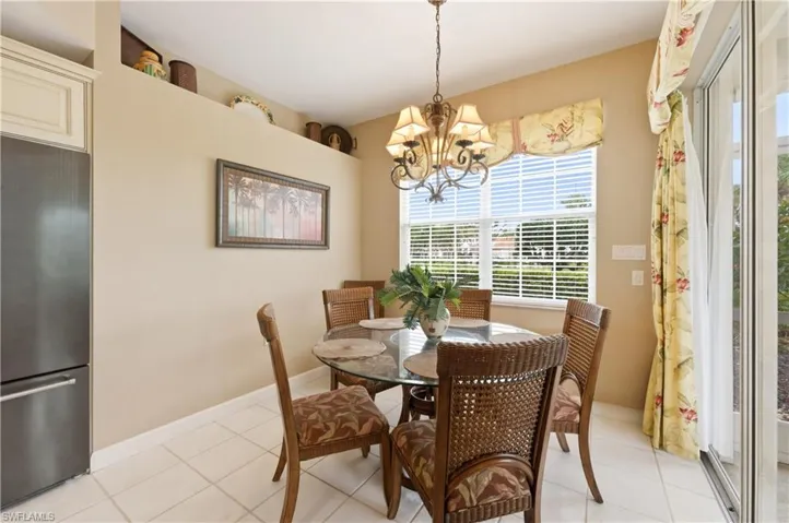 Dining area featuring a decorative chandelier, white tile flooring, and a large window with horizontal blinds