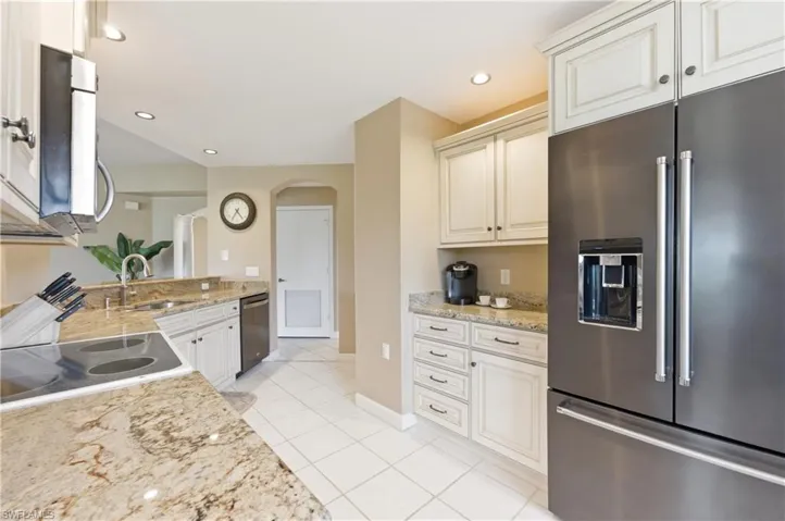 Kitchen featuring granite countertops, white cabinetry, stainless steel appliances, and tile flooring