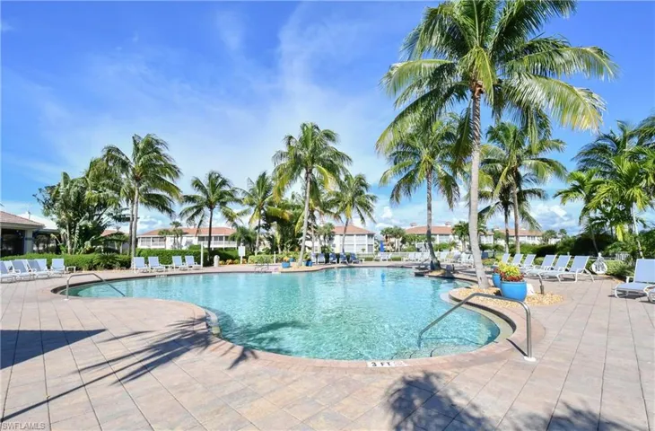Expansive outdoor pool area featuring a large swimming pool with clear water, surrounded by a paved deck