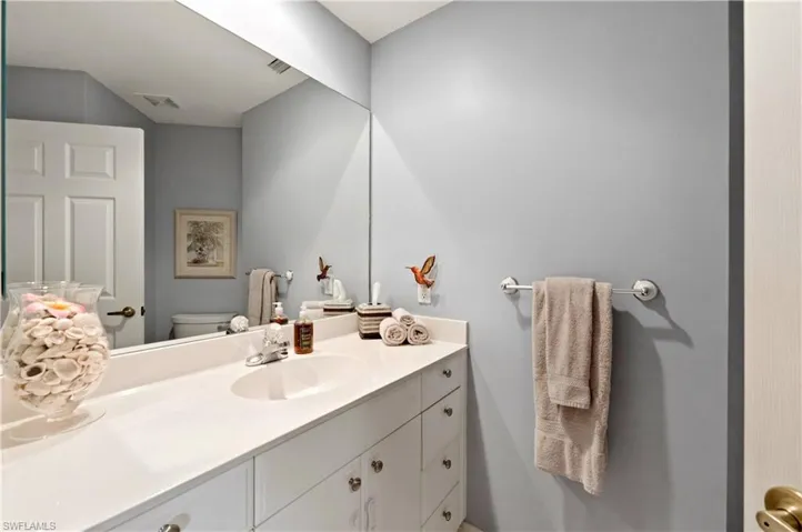 Vanity featuring a white countertop with an integrated sink, polished chrome faucet, and white cabinetry with silver-tone hardware
