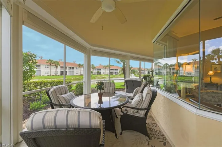 Screened outdoor living area featuring a ceiling fan, glass-top table, and a partial outdoor rug