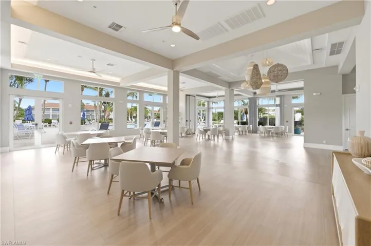 Spacious common area featuring light wood-finish flooring, high ceilings with recessed lighting, and multiple ceiling fans