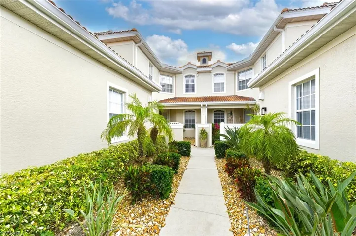 Mediterranean-inspired exterior featuring stucco siding, tile roofing, multiple windows, and a central walkway
