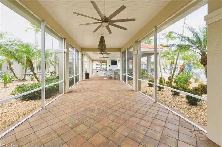 Expansive covered patio featuring patterned tile flooring, multiple ceiling fans, and a large hanging light fixture