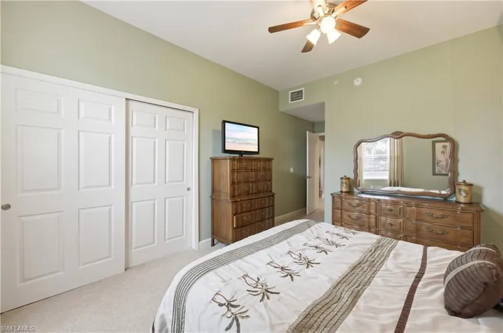 Recessed lighting and a ceiling fan illuminate this space featuring light green walls and neutral carpeting