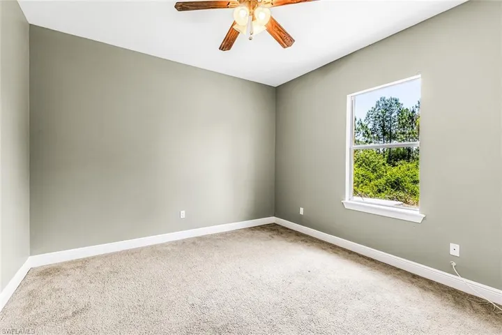 Carpeted empty room featuring ceiling fan and baseboards