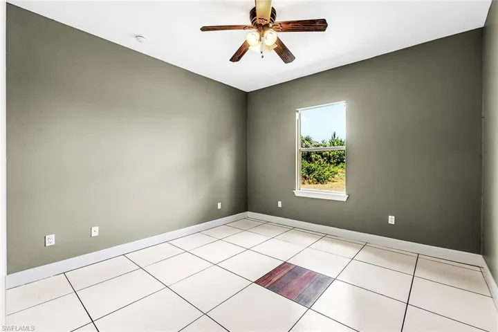 Spare room with ceiling fan, baseboards, light tile patterned floors, and a smoke detector