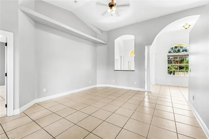 Spare room with ceiling fan, light tile patterned floors, arched walkways, vaulted ceiling, and baseboards