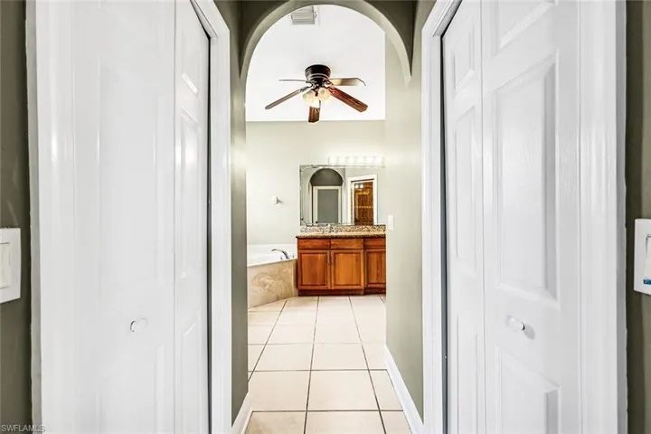 Bathroom featuring a closet, a ceiling fan, tile patterned flooring, and a garden tub